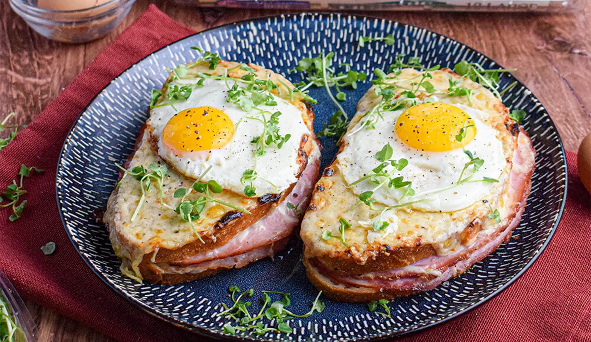 Two ham and cheese breakfast plates topped with fried eggs